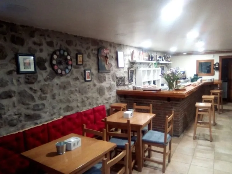 El comedor de La Tienduca, con pared de piedra y bancos rojos